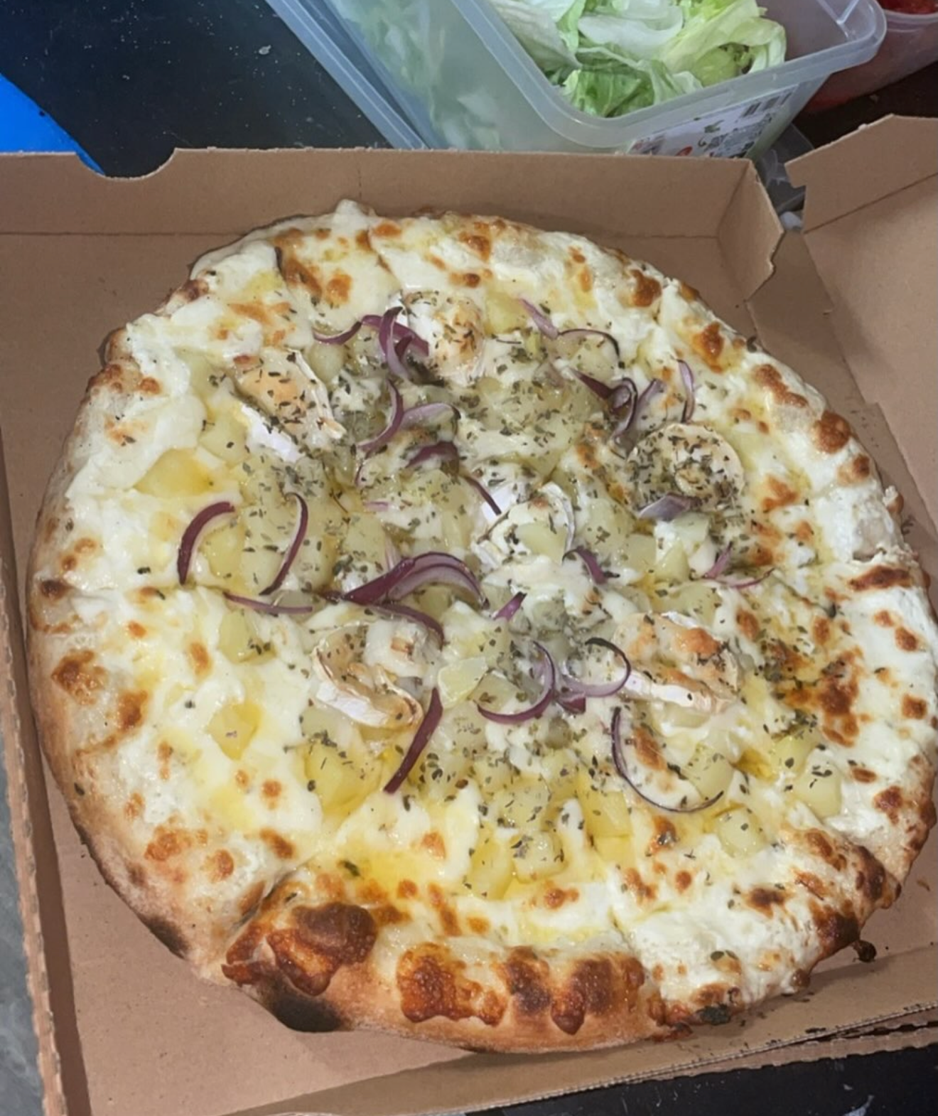 Pizza aux pommes de terre, mozzarella et oignons, servie dans sa boîte
