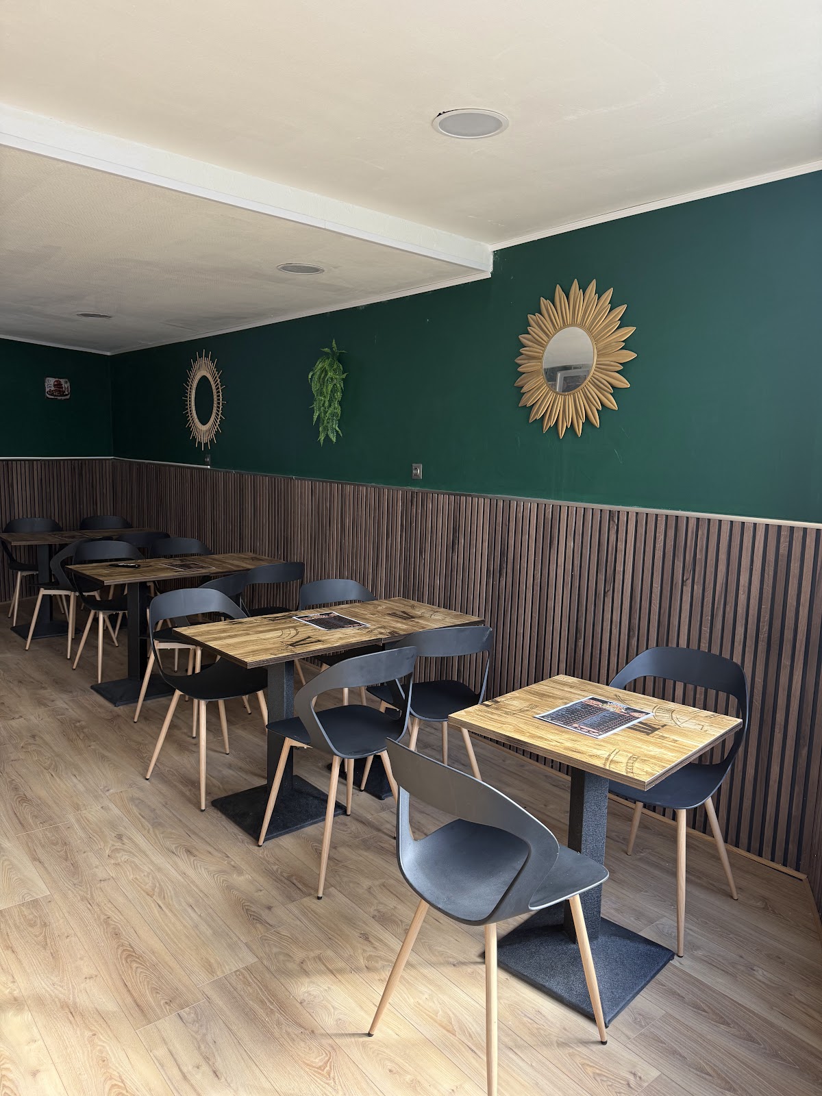 Salle de restaurant, tables en bois clair avec chaises noires, miroirs décorés